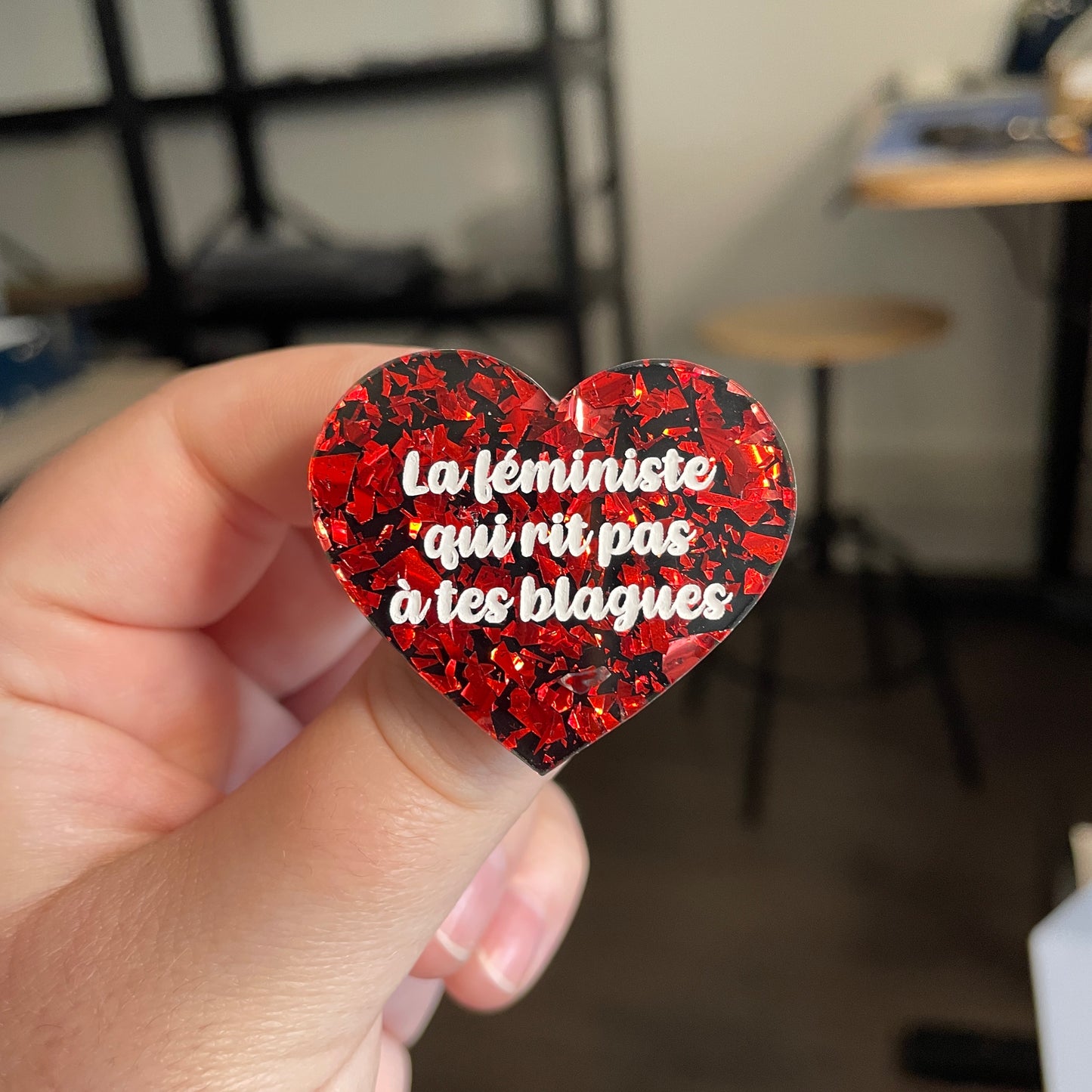 [CONTRÔLE TECHNIQUE] Broche "La féministe qui rit pas à tes blagues" en acrylique noire avec des éclats de confettis rouges