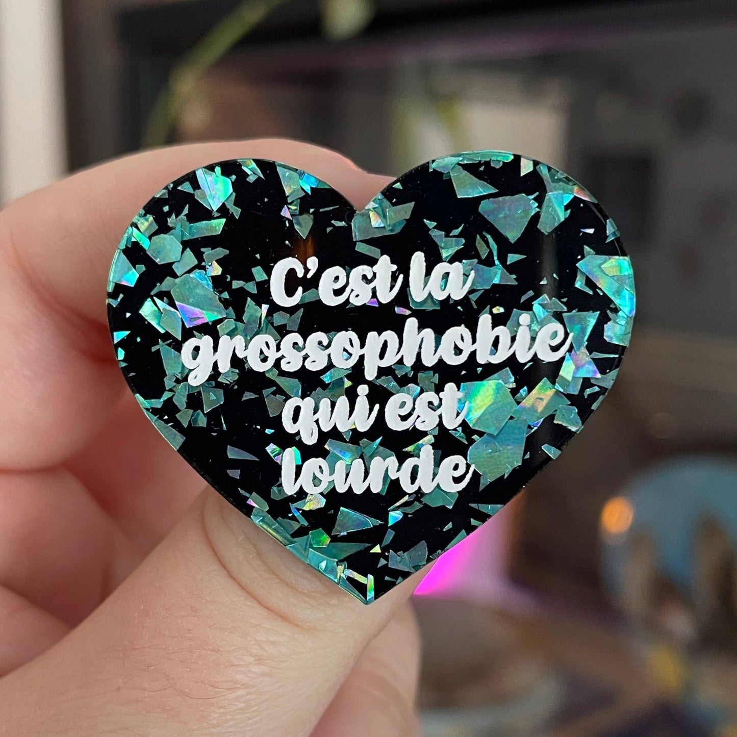 Broche "C'est la grossophobie qui est lourde" en acrylique noire avec des éclats de confettis turquoise