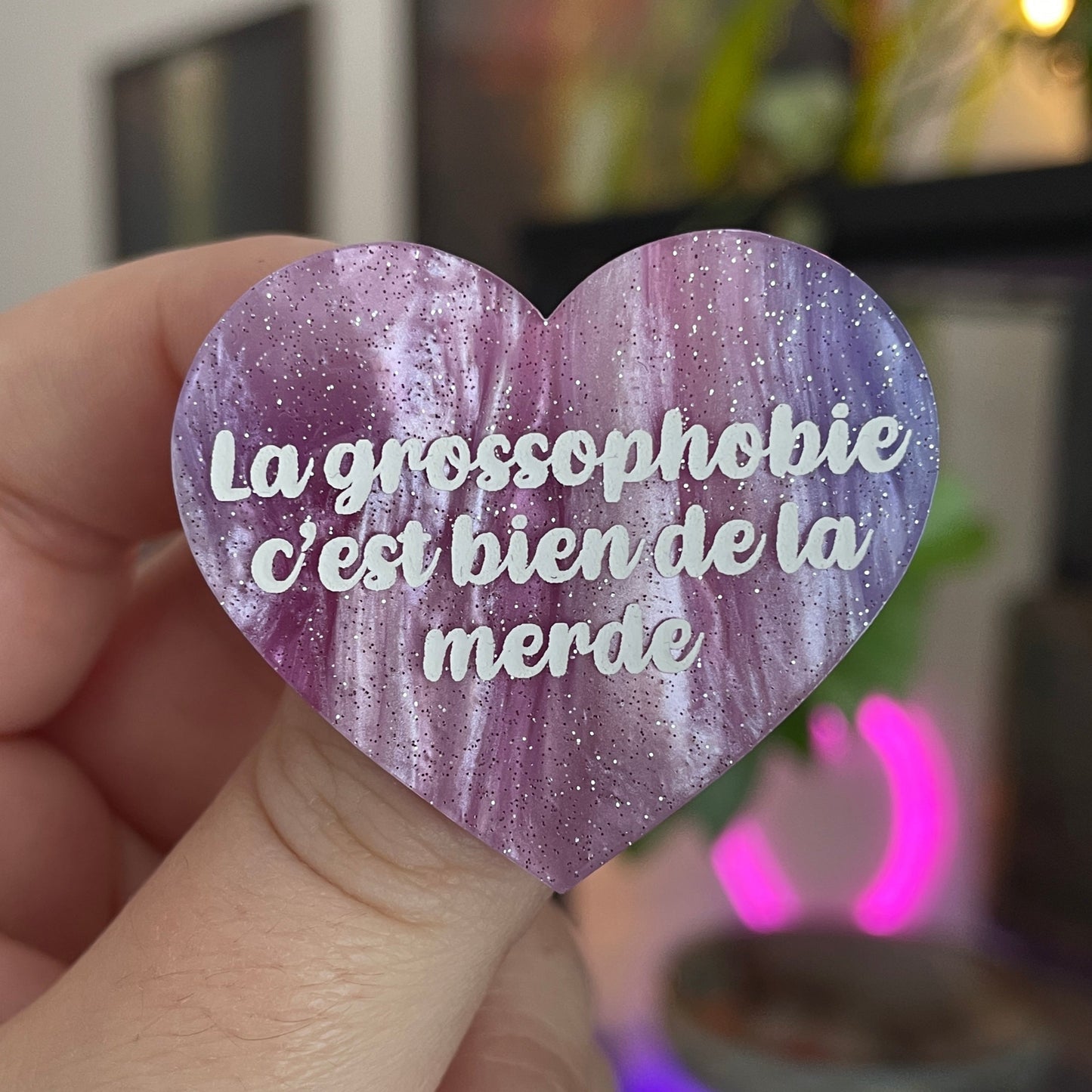 Broche "La grossophobie c'est bien de la merde" en acrylique marbrée violette, rose et blanche à paillettes