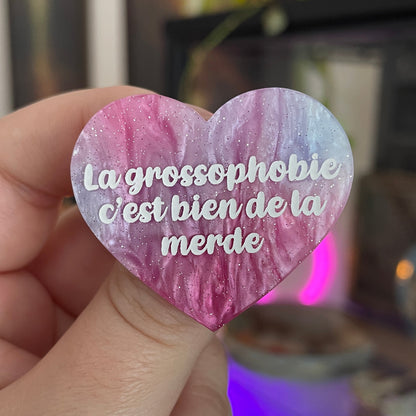 Broche "La grossophobie c'est bien de la merde" en acrylique marbrée violette, rose et blanche à paillettes