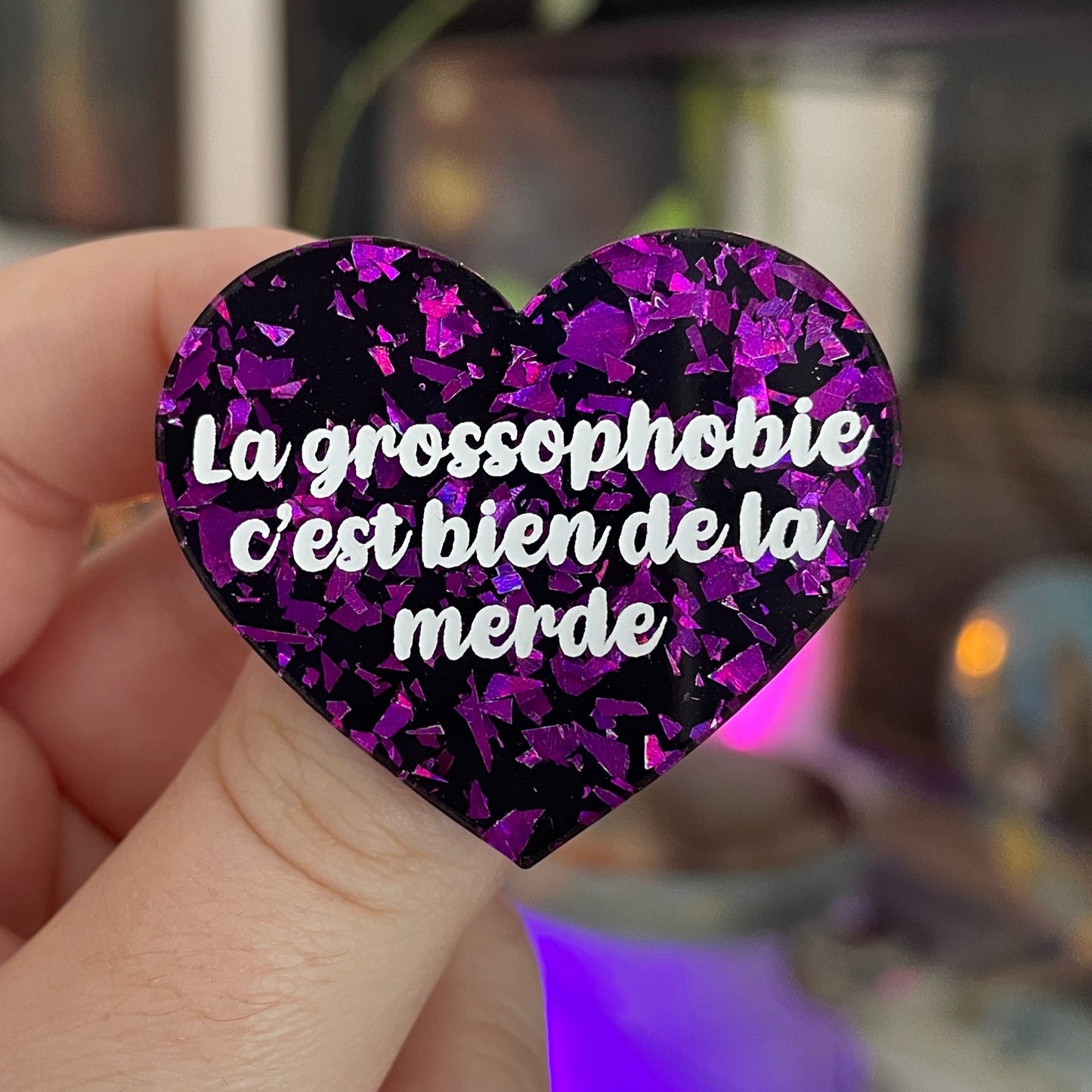 Broche "La grossophobie c'est bien de la merde" en acrylique noire avec des éclats de confettis violets