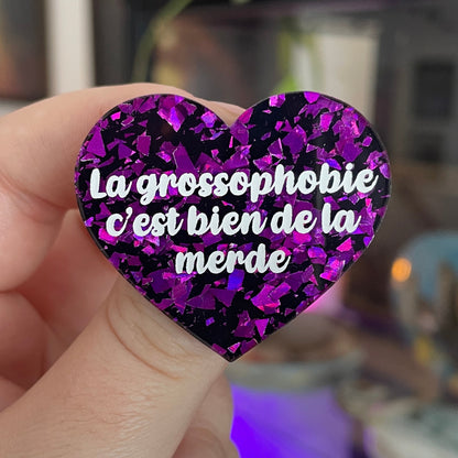 Broche "La grossophobie c'est bien de la merde" en acrylique noire avec des éclats de confettis violets