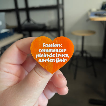 [CONTRÔLE TECHNIQUE] Broche "Passion : commencer plein de trucs, ne rien finir" en acrylique marbrée orange et dorée à paillettes