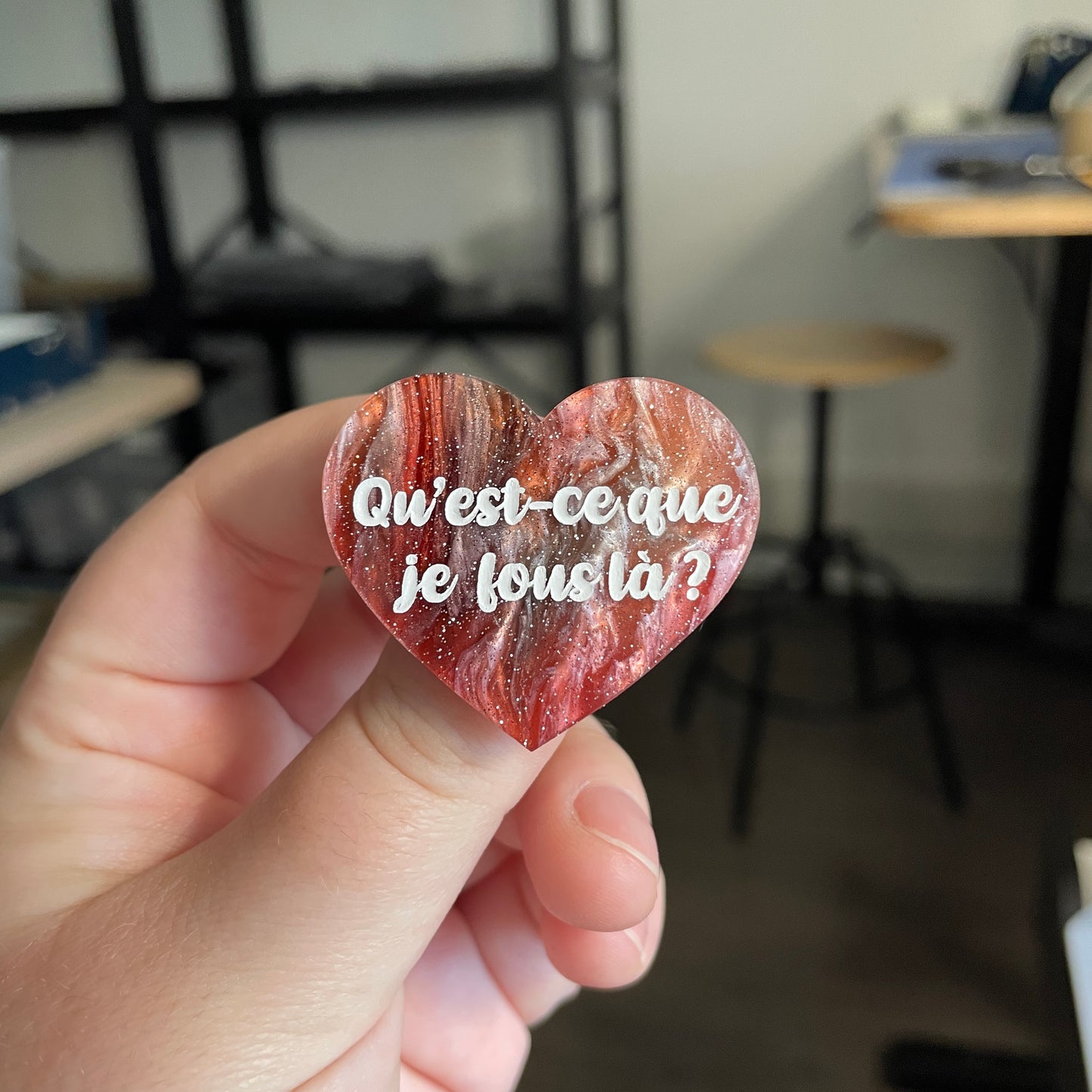 [CONTRÔLE TECHNIQUE] Broche "Qu'est-ce que je fous là ?" en acrylique marbrée rouge, verte, marron et blanche à paillettes
