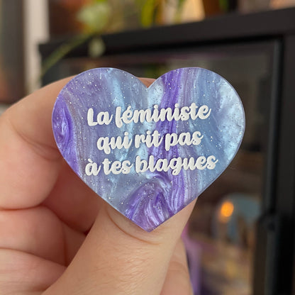 Broche "La féministe qui rit pas à tes blagues" en acrylique marbrée bleue et violette à paillettes