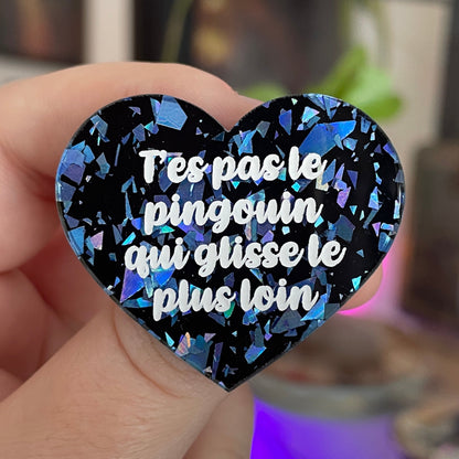 Broche "T'es pas le pingouin qui glisse le plus loin" en acrylique noire avec des éclats de confettis bleus