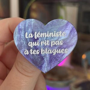 Broche "La féministe qui rit pas à tes blagues" en acrylique marbrée bleue et violette à paillettes