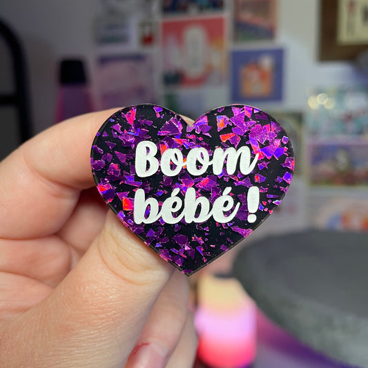 Broche "Boom bébé !" en acrylique noire avec des éclats de confettis violets
