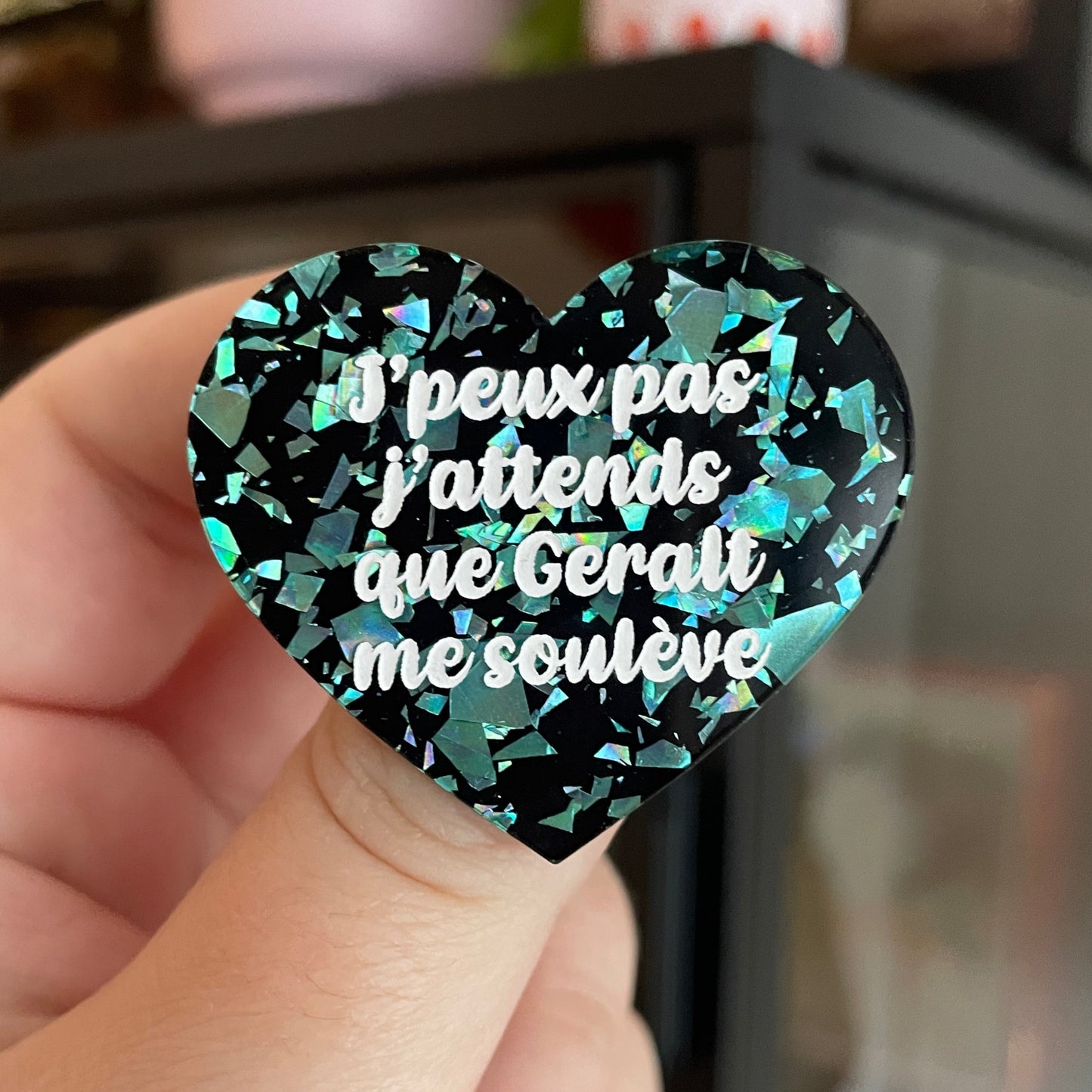 Broche "J'peux pas j'attends que Geralt me soulève" en acrylique noire avec des éclats de confettis turquoise