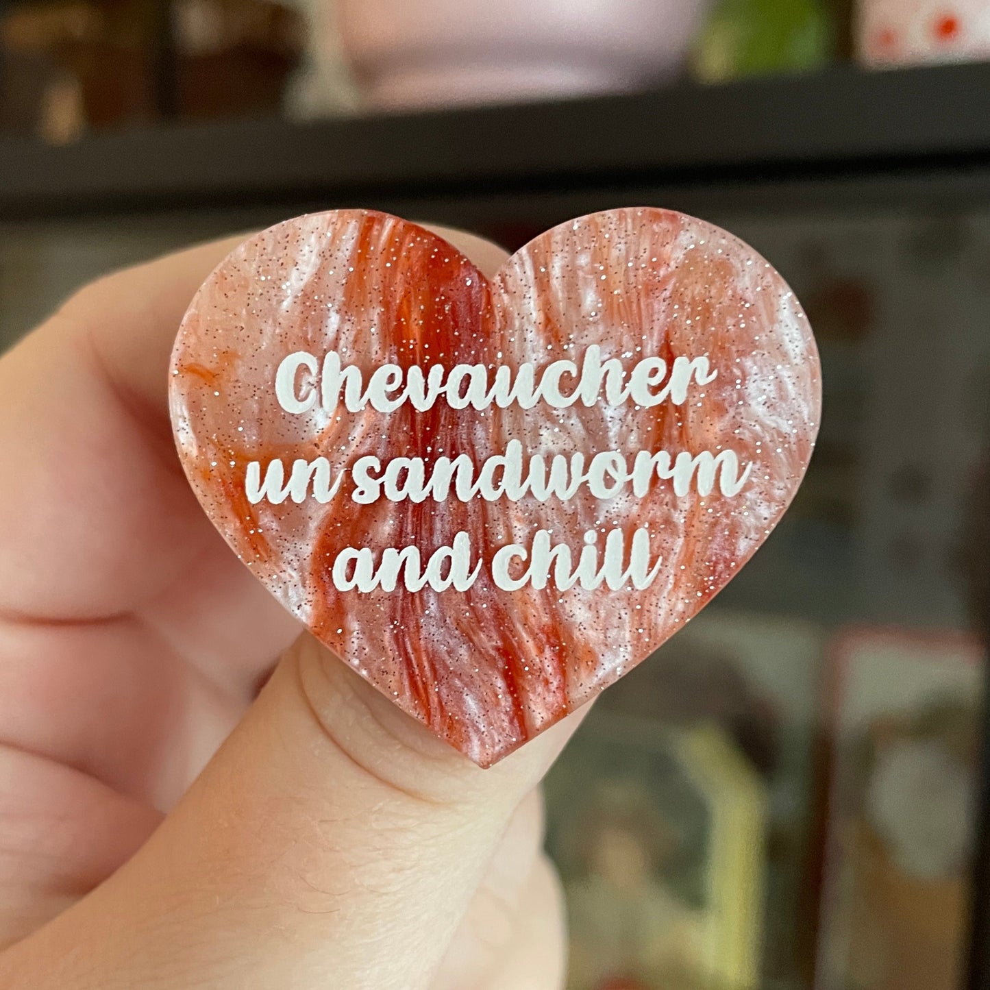 Broche "Chevaucher un sandworm and chill" en acrylique marbrée blanche et orange à paillettes