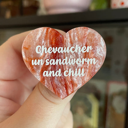 Broche "Chevaucher un sandworm and chill" en acrylique marbrée blanche et orange à paillettes