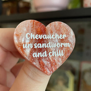 Broche "Chevaucher un sandworm and chill" en acrylique marbrée blanche et orange à paillettes