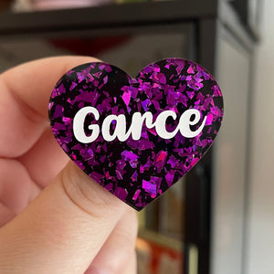 Broche "Garce" en acrylique noire avec des éclats de confettis violets