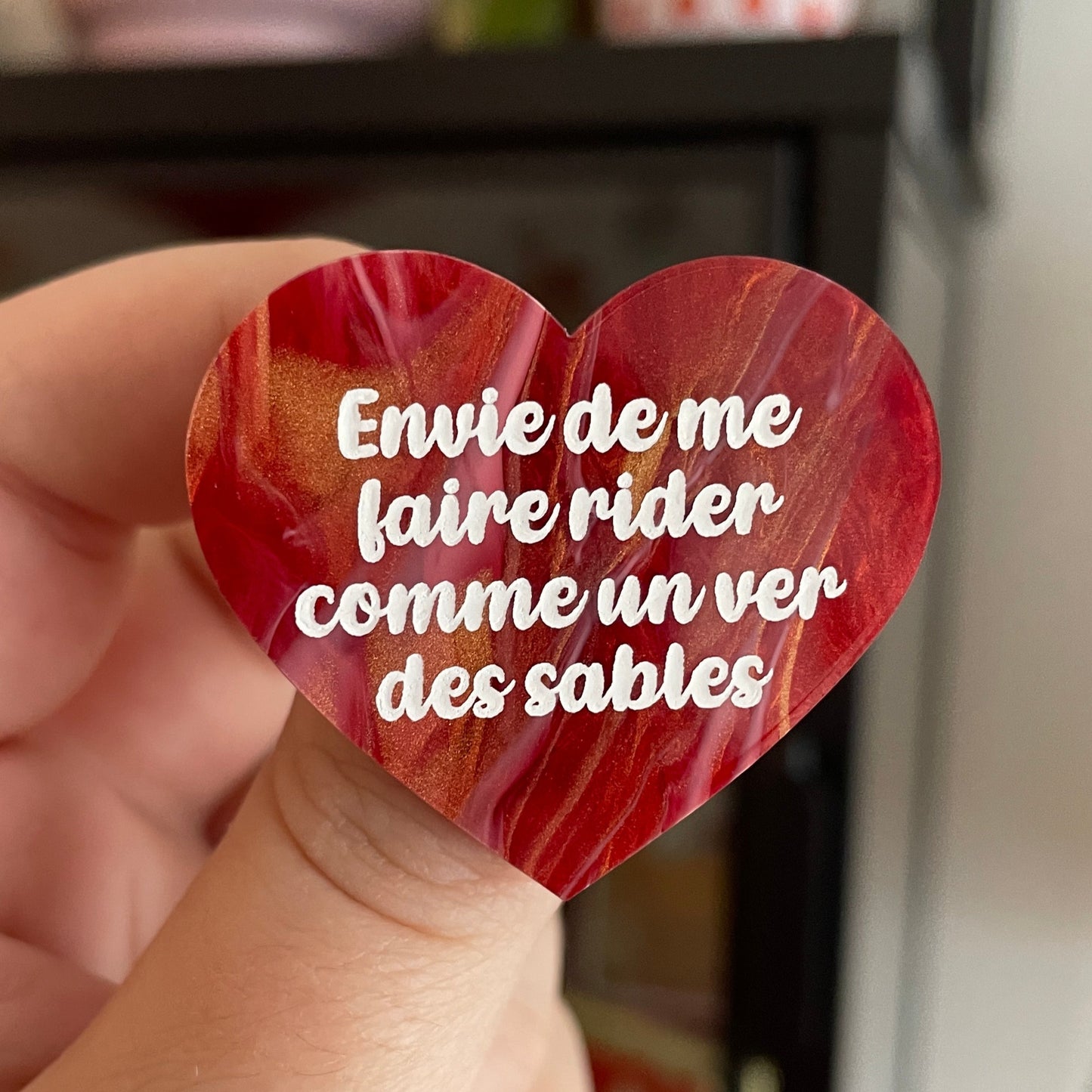 Broche "Envie de me faire rider comme un ver des sables" en acrylique marbrée rouge, dorée et blanche