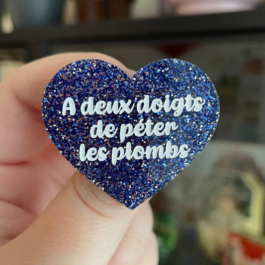 Broche "A deux doigts de péter les plombs" en acrylique à paillettes bleues et argentées