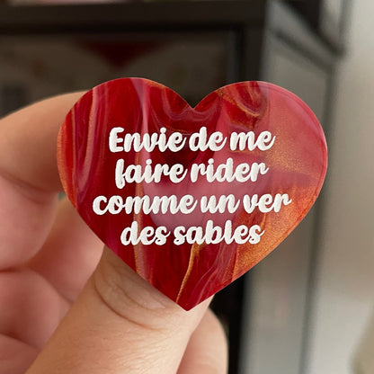 Broche "Envie de me faire rider comme un ver des sables" en acrylique marbrée rouge, dorée et blanche
