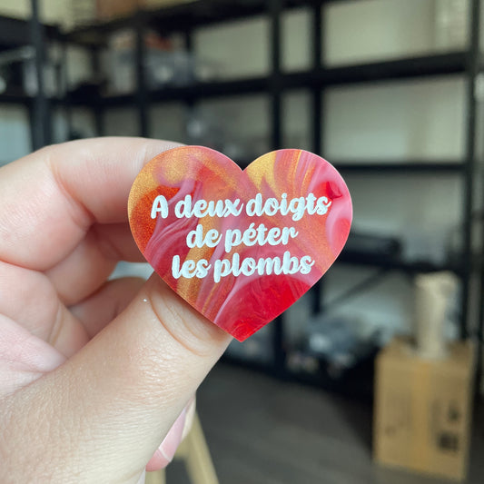 Broche "A deux doigts de péter les plombs" en acrylique marbrée rouge, blanche et dorée