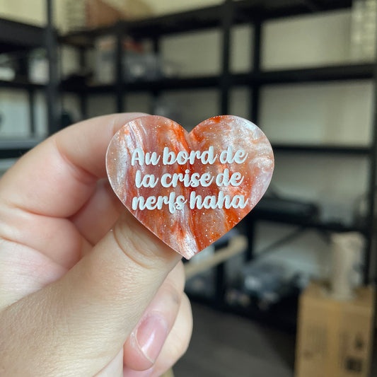 Broche "Au bord de la crise de nerfs haha" en acrylique marbrée orange, blanche et violette à paillettes