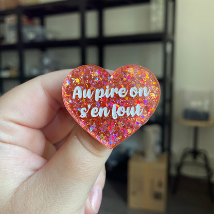 Broche "Au pire on s'en fout" en acrylique semi transparente avec des paillettes corail