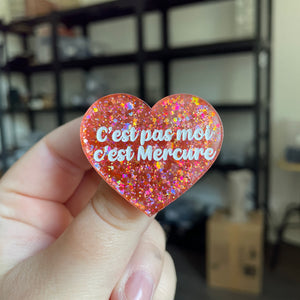 Broche "C'est pas moi c'est Mercure" en acrylique semi transparente avec des paillettes corail