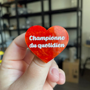 Broche "Championne du quotidien" en acrylique marbrée orange à paillettes
