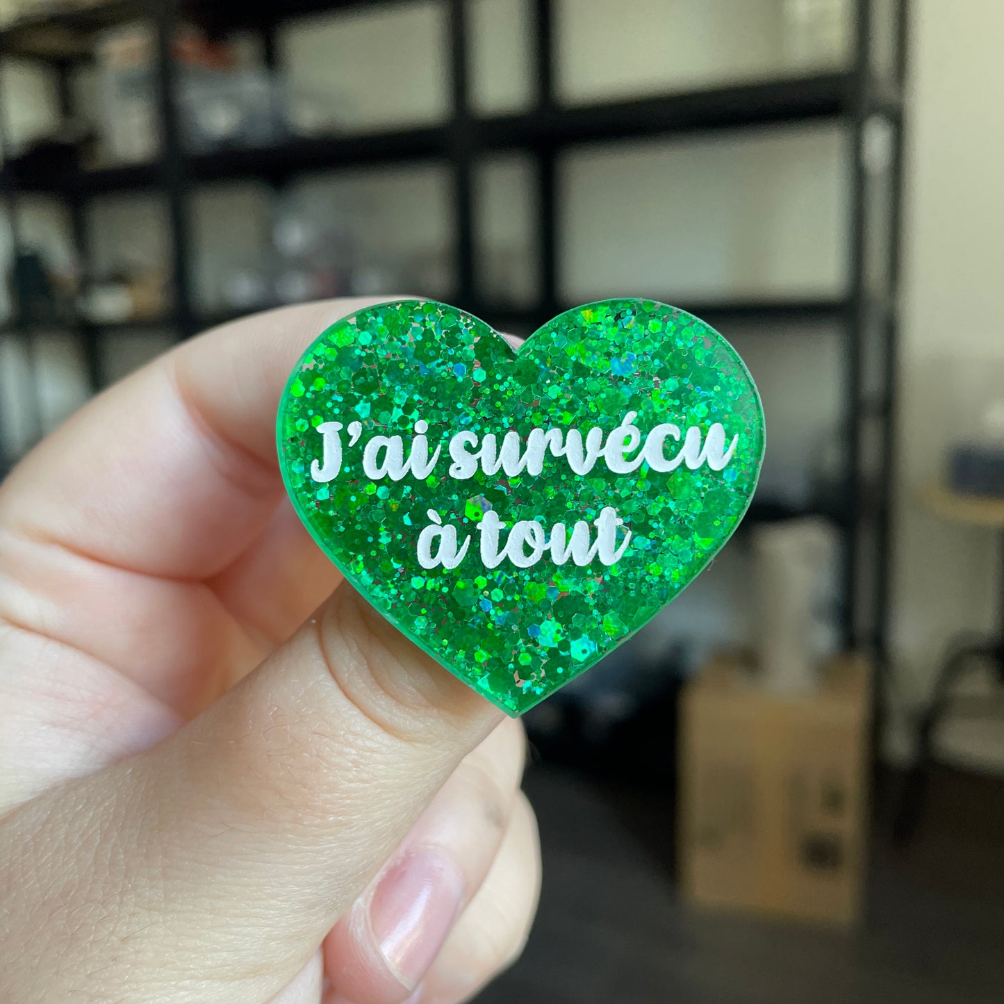 Broche "J'ai survécu à tout" en acrylique semi transparente avec des paillettes vertes