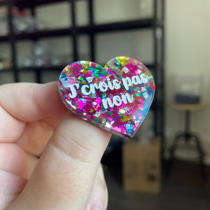 Broche "J'crois pas non" en acrylique transparente avec des éclats de confettis roses et multicolores