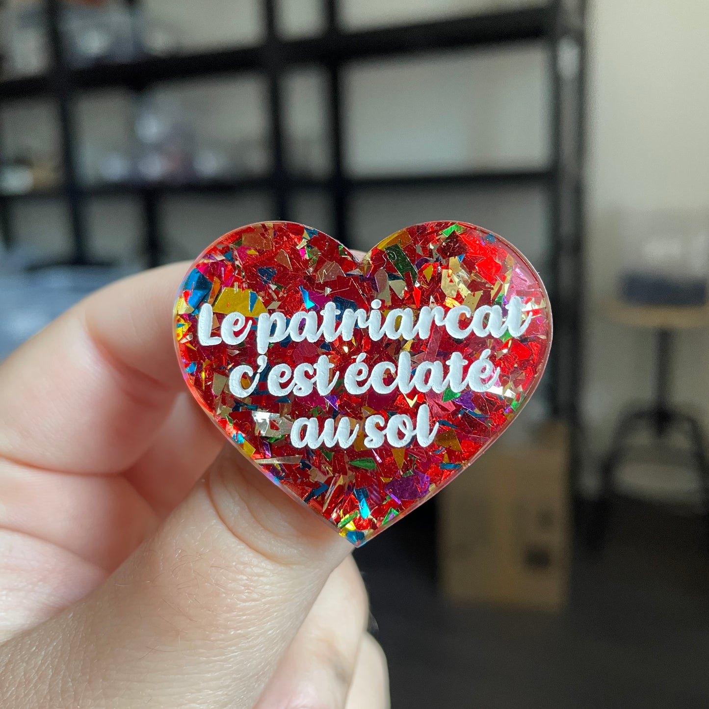 Broche "Le patriarcat c'est éclaté au sol" en acrylique transparente avec des éclats de confettis rouges et multicolores