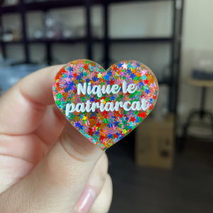 Broche "Nique le patriarcat" en acrylique semi transparente avec des confettis étoiles multicolores