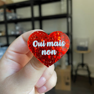 Broche "Oui mais non" en acrylique semi transparente avec des confettis rouges