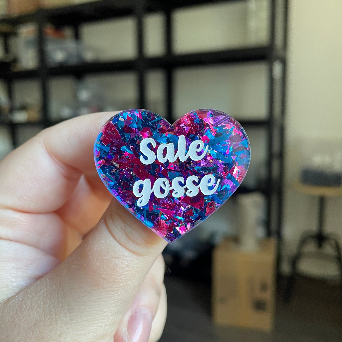 Broche "Sale gosse" en acrylique transparente avec des éclats de confettis bleus et violets/roses