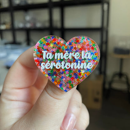 Broche "Ta mère la sérotonine" en acrylique semi transparente avec des confettis étoiles multicolores