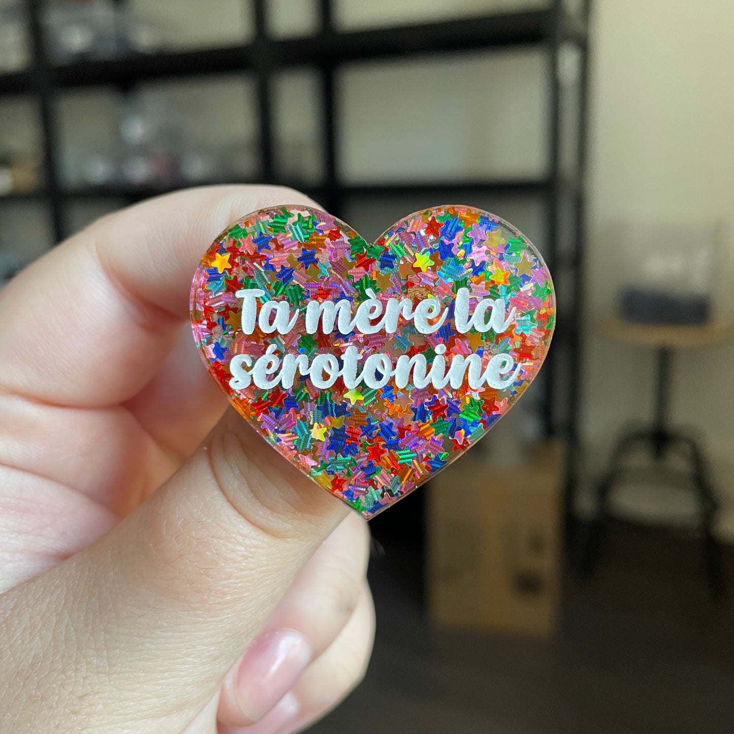 Broche "Ta mère la sérotonine" en acrylique semi transparente avec des confettis étoiles multicolores