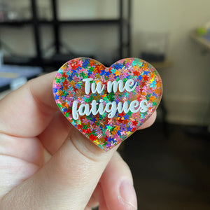 Broche "Tu me fatigues" en acrylique semi transparente avec des paillettes étoiles multicolores