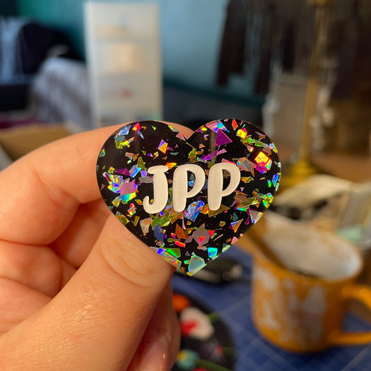 [Contrôle technique] Broche "JPP" en acrylique noire avec des éclats de confettis multicolores