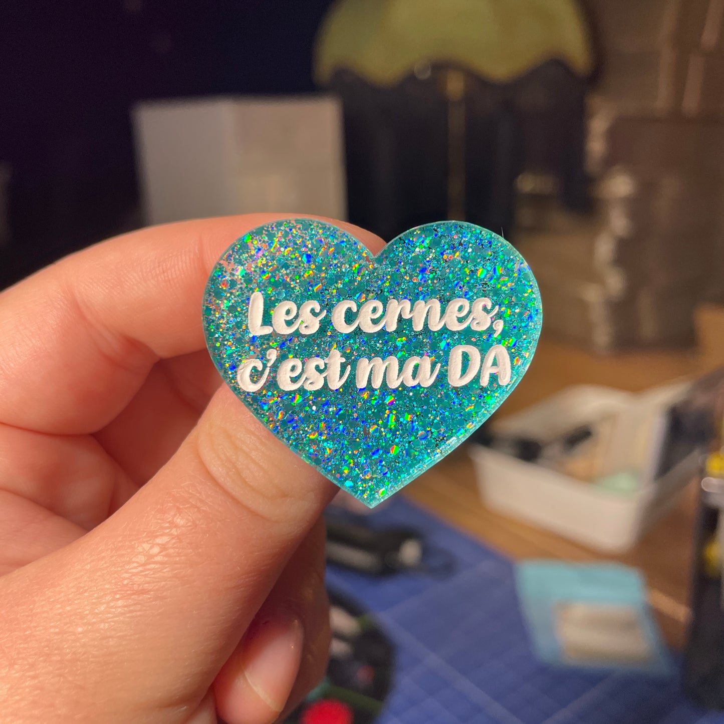 [Contrôle technique] Broche "Les cernes c'est ma DA" en acrylique à paillettes turquoise