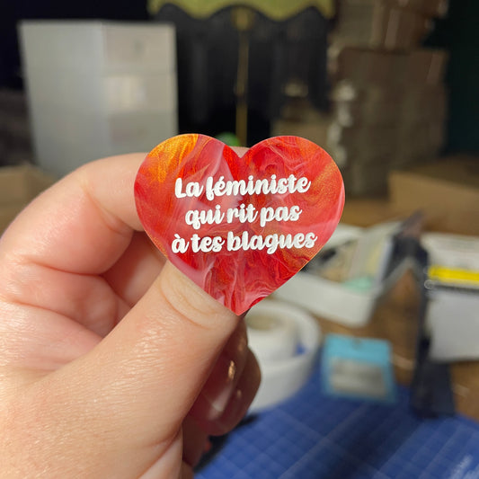 [Contrôle technique] Broche "La féministe qui rit pas à tes blagues" en acrylique marbrée rouge, blanche et dorée