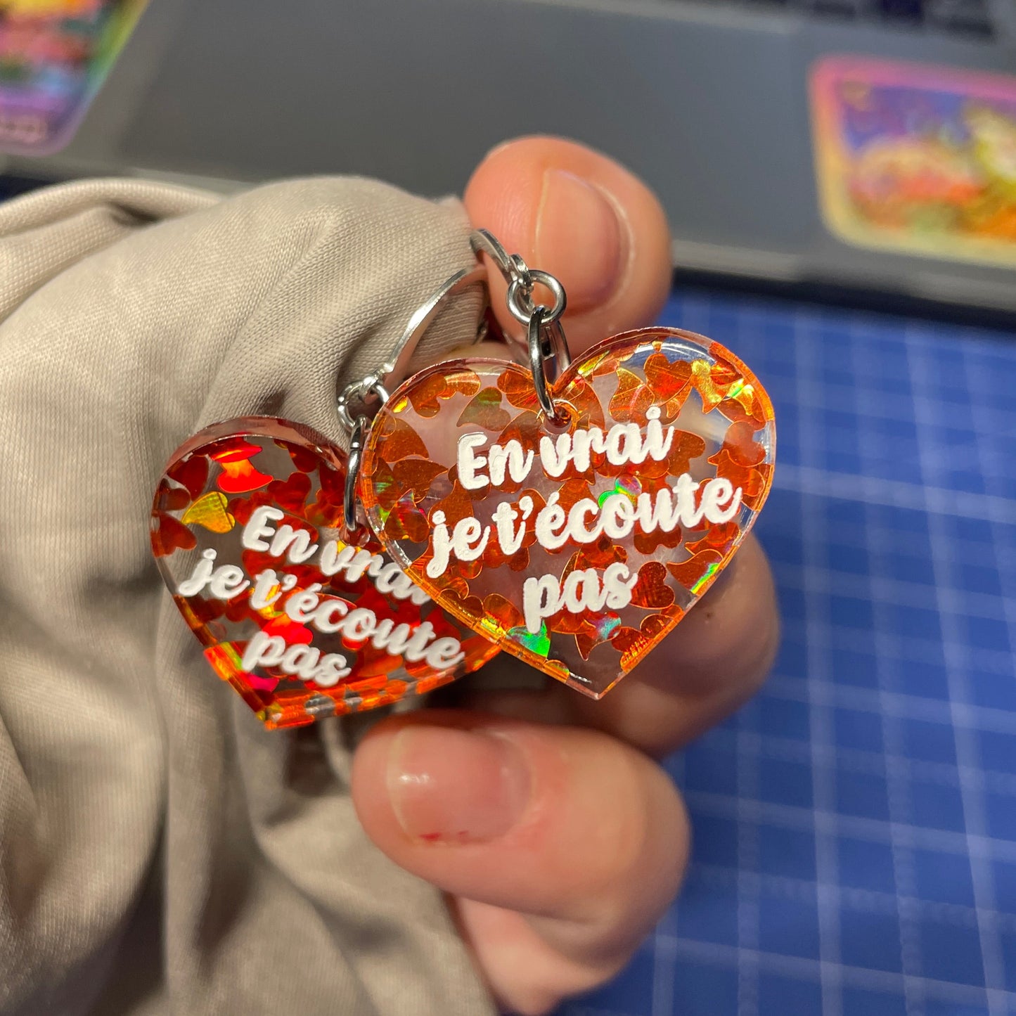 Petites boucles d'oreilles coeurs pendantes "En vrai je t'écoute pas" en acrylique transparente avec des coeurs oranges