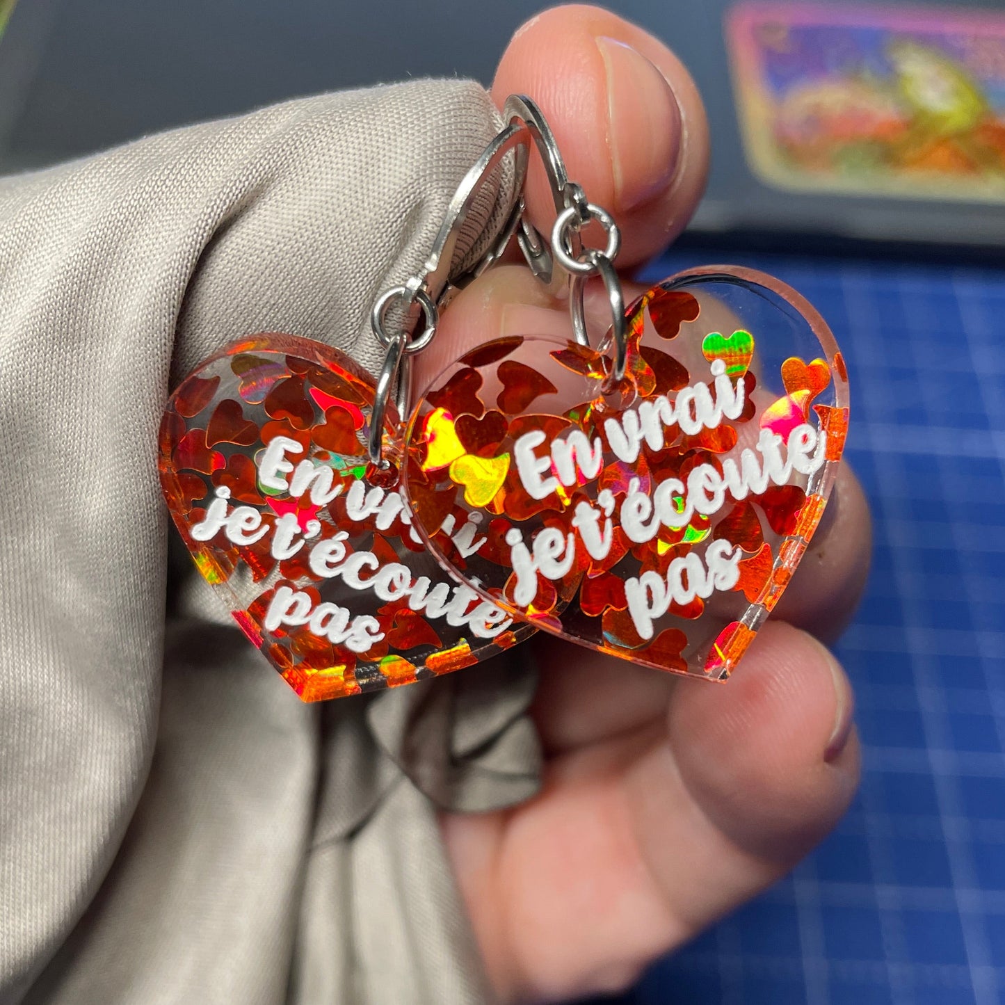 Petites boucles d'oreilles coeurs pendantes "En vrai je t'écoute pas" en acrylique transparente avec des coeurs oranges