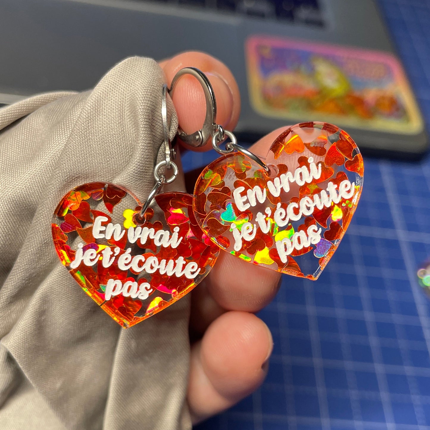 Petites boucles d'oreilles coeurs pendantes "En vrai je t'écoute pas" en acrylique transparente avec des coeurs oranges