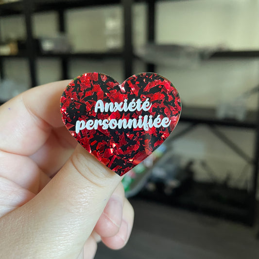 Broche "Anxiété personnifiée" en acrylique noire avec des éclats de confettis rouges