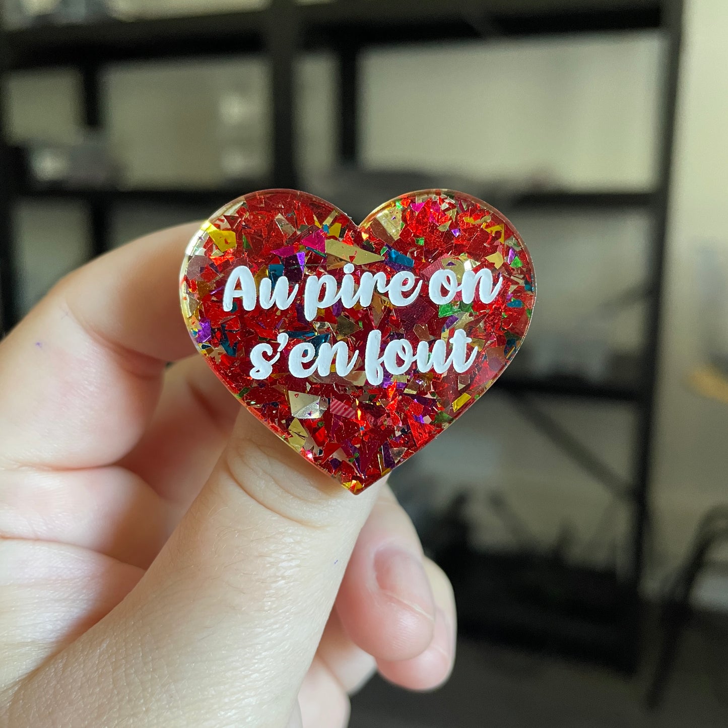 Broche "Au pire on s'en fout" en acrylique transparente avec des confettis rouges et multicolores