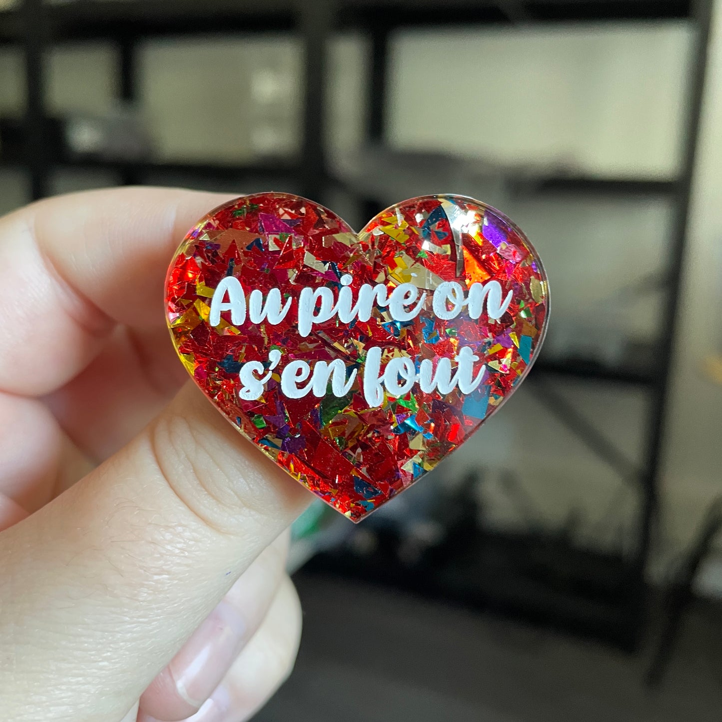 Broche "Au pire on s'en fout" en acrylique transparente avec des confettis rouges et multicolores