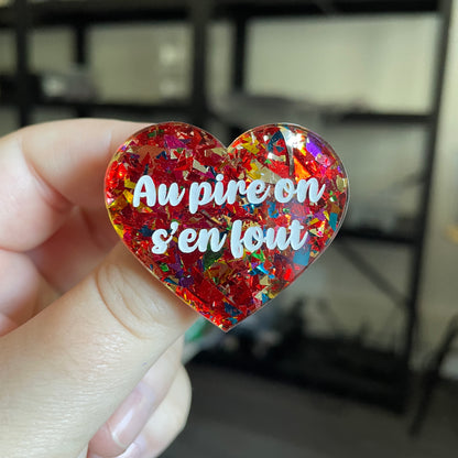 Broche "Au pire on s'en fout" en acrylique transparente avec des confettis rouges et multicolores