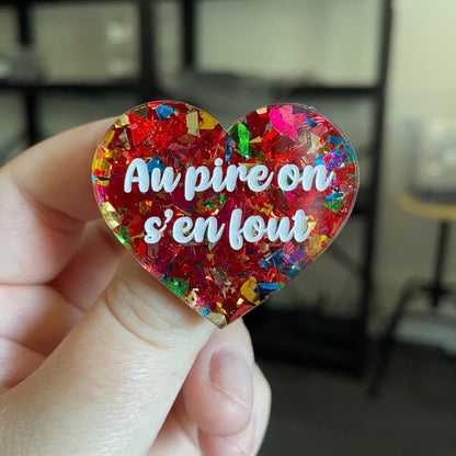 Broche "Au pire on s'en fout" en acrylique transparente avec des confettis rouges et multicolores