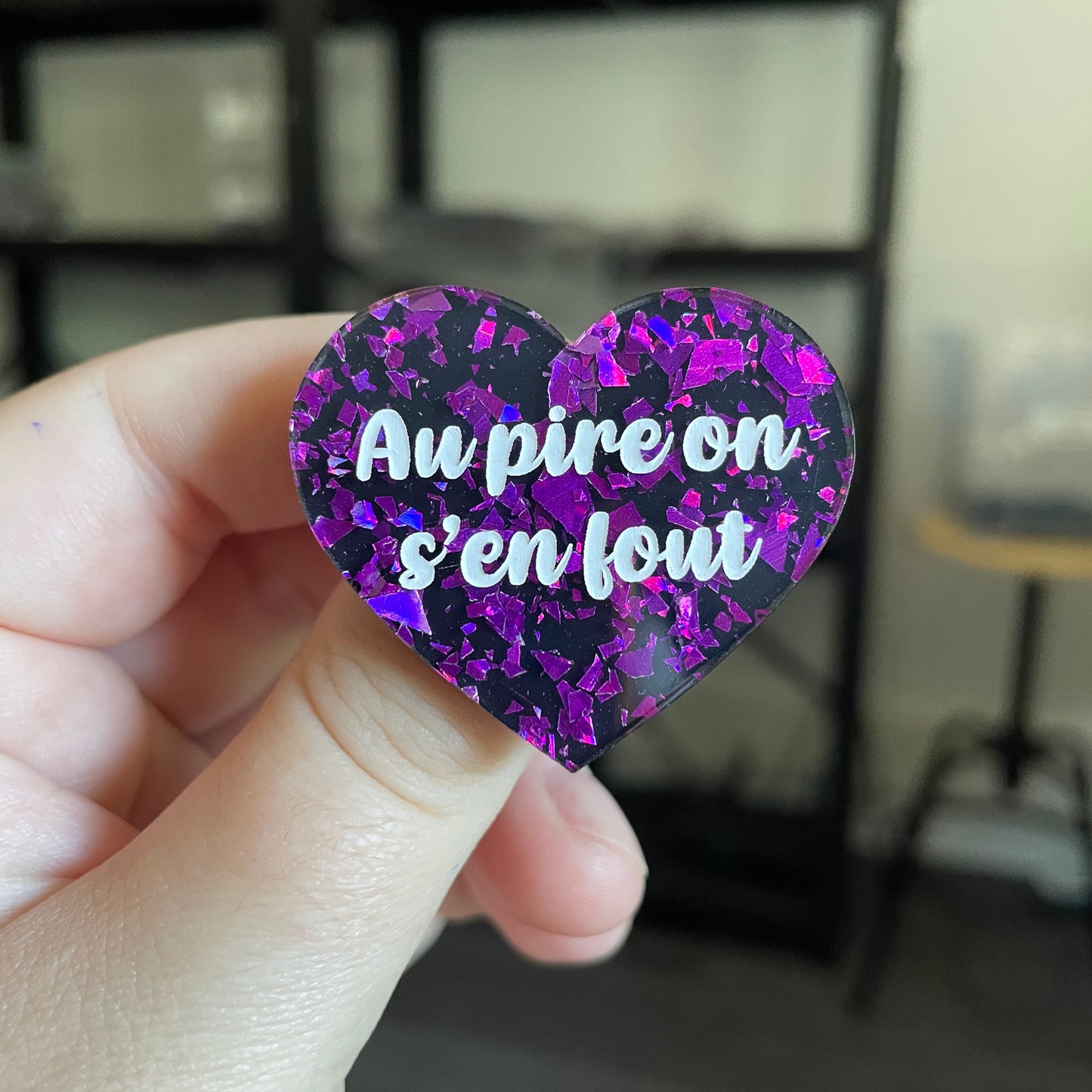 Broche "Au pire on s'en fout" en acrylique noire avec des éclats de confettis violets