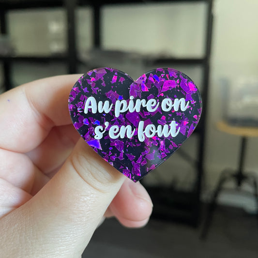 Broche "Au pire on s'en fout" en acrylique noire avec des éclats de confettis violets