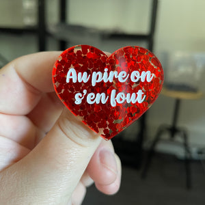 Broche "Au pire on s'en fout" en acrylique semi transparente avec des confettis rouges