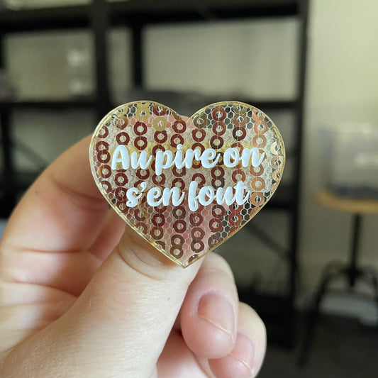 Broche "Au pire on s'en fout" en acrylique japonaise transparente avec des sequins dorés