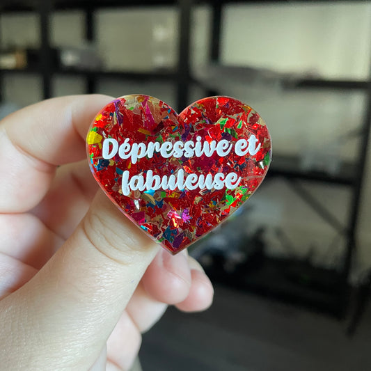 Broche "Dépressive et fabuleuse" en acrylique transparente avec des éclats de confettis rouges et multicolores